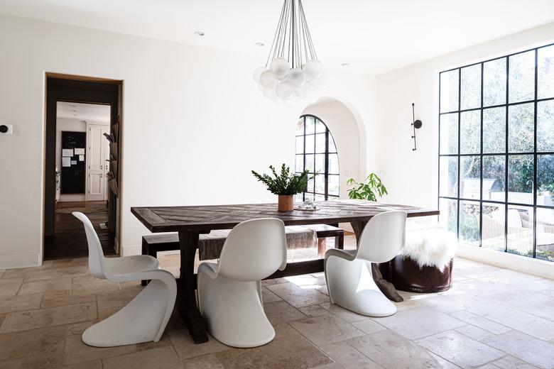 Minimalist dining room idea with Panton chairs at wood dining table on limestone tiled floor