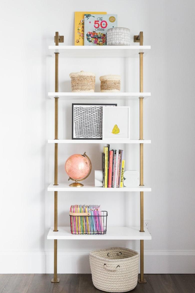 Minimalist toy storage idea with white and brass shelf with books and toys