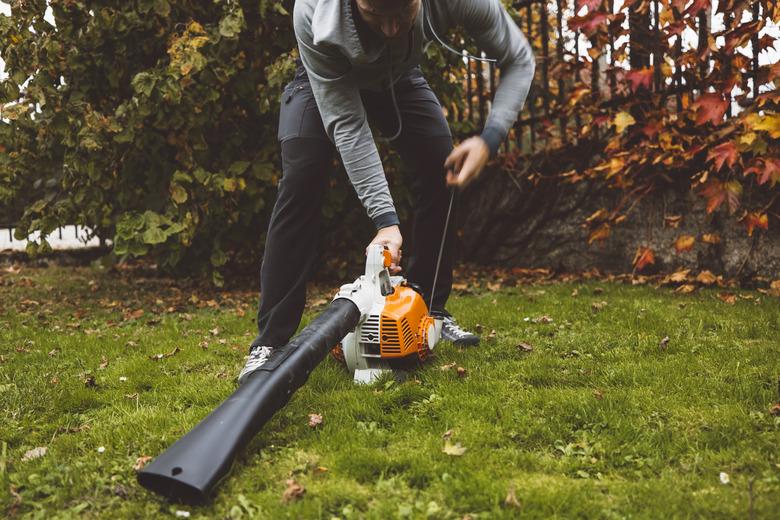 Starting a leaf blower by pulling the starter cord..