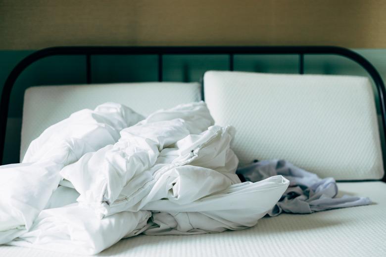 Duvet, and pillows on a bed without cover in a bedroom