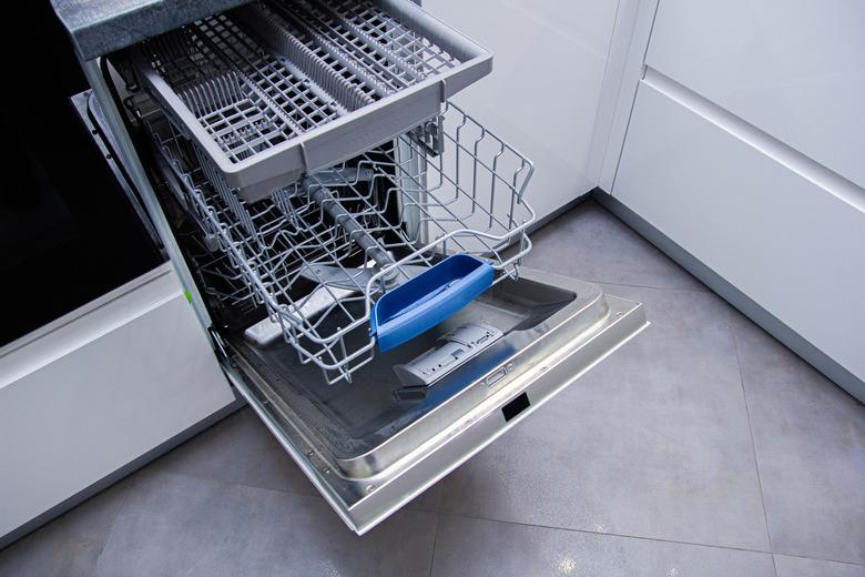 open modern dishwasher in the kitchen; built-in appliances in furniture.