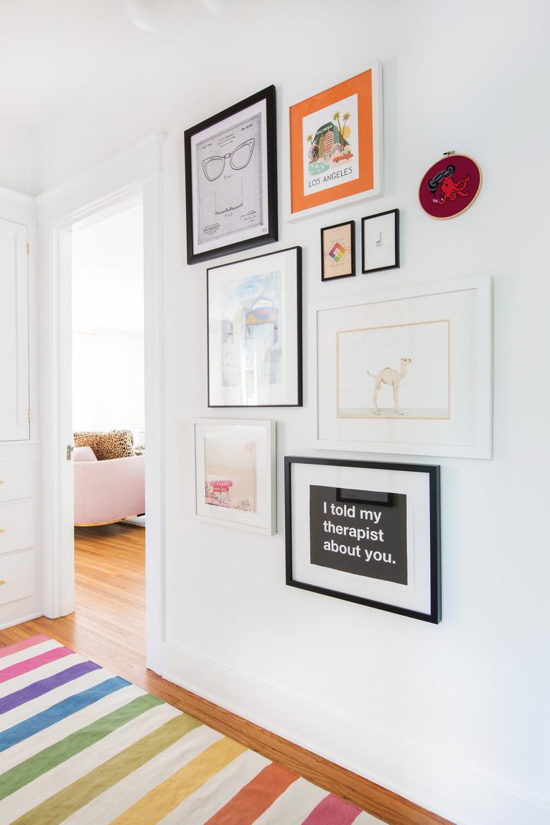 hallway with rainbow rug and framed prints on the wall