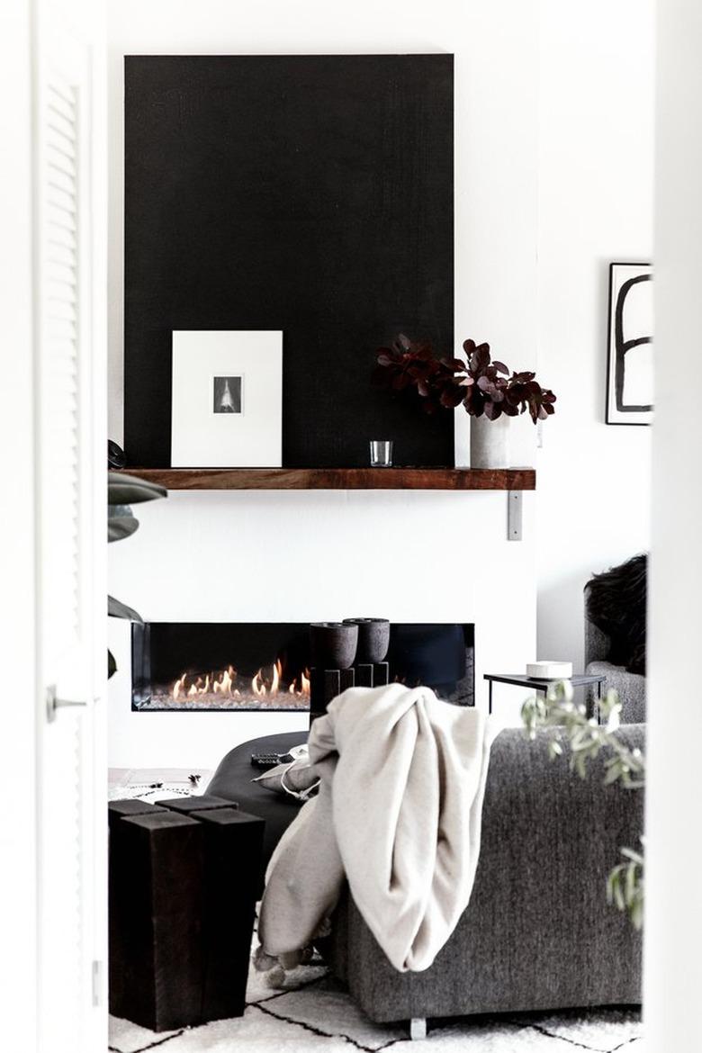 Modern black and white living room with fireplace and wood mantel