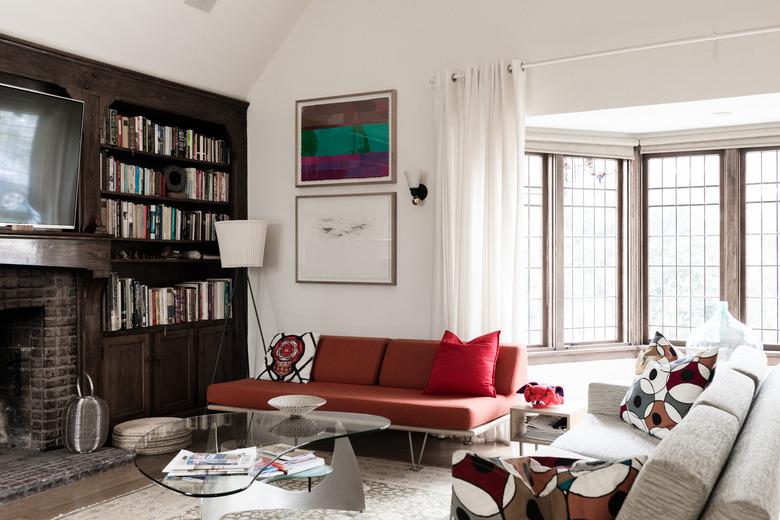 Large living room with dark wood bookshelf and white bay window curtains