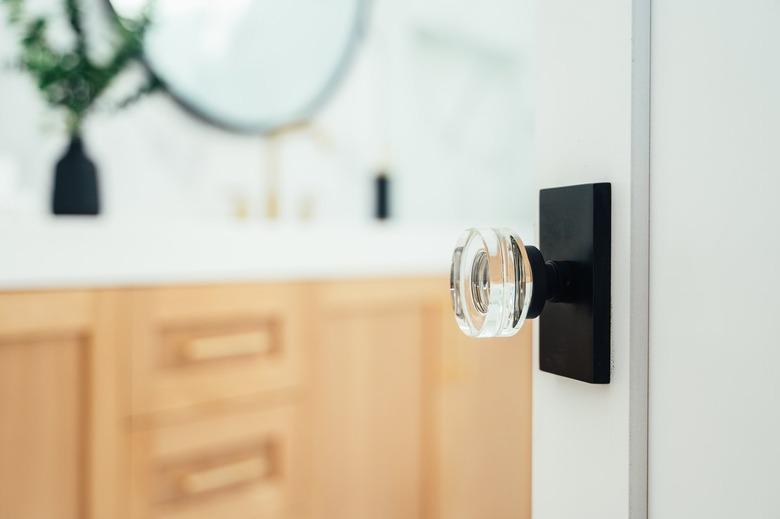 Clear crystal door knob on a white door leading to a bathroom