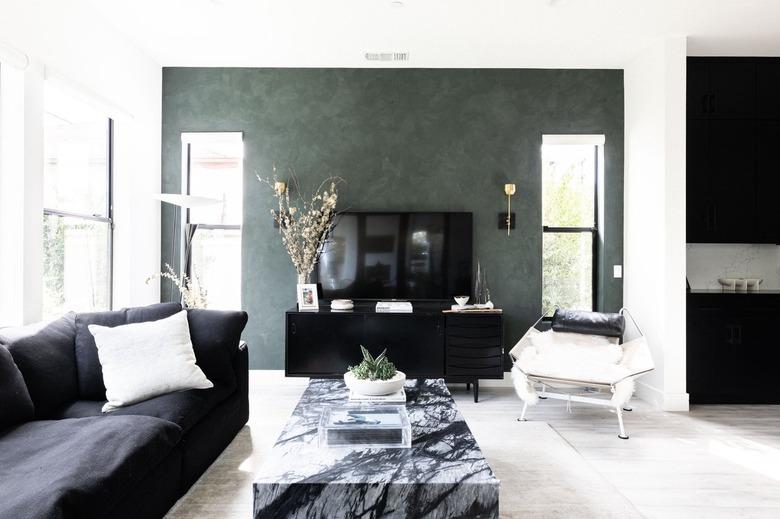 Modern living room with green walls and black-white furnishings