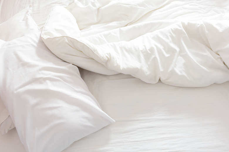 Top view of an unmade bed with crumpled bed sheet.