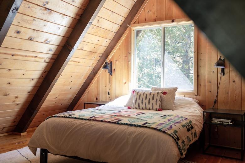 All-wood interior bedroom with triangle archway with patterned bedding and pillow and matching side tables