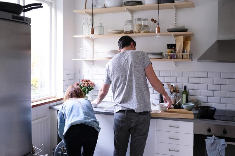 Rear view of couple working in kitchen at home