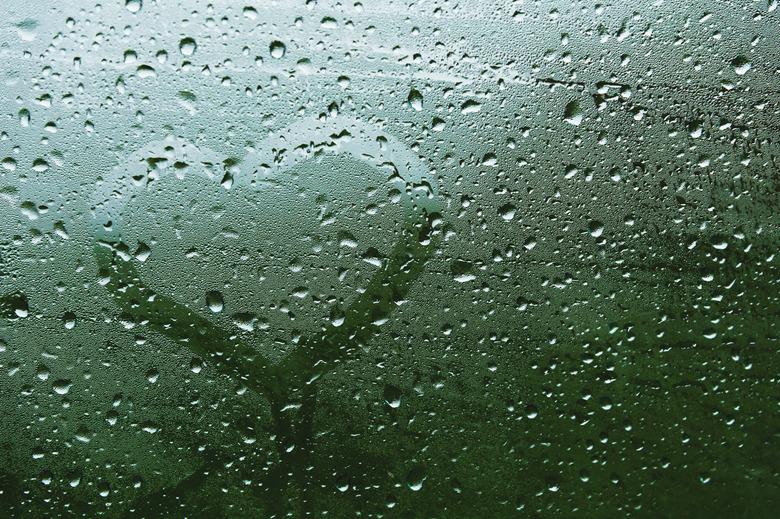 Close-up Summer rain inscription on sweaty glass. Symbol of heart and love on green blurred background