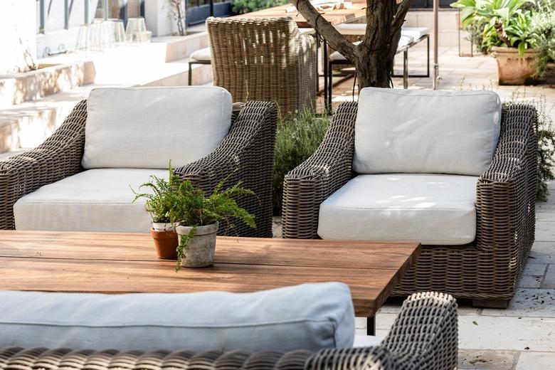 White cushioned patio chairs with a wood coffee table and plants.