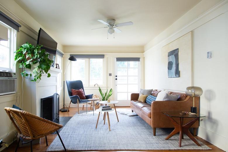 a living room with a leather couch, mid-century side tables, and a lamp with a glass globe for a shade