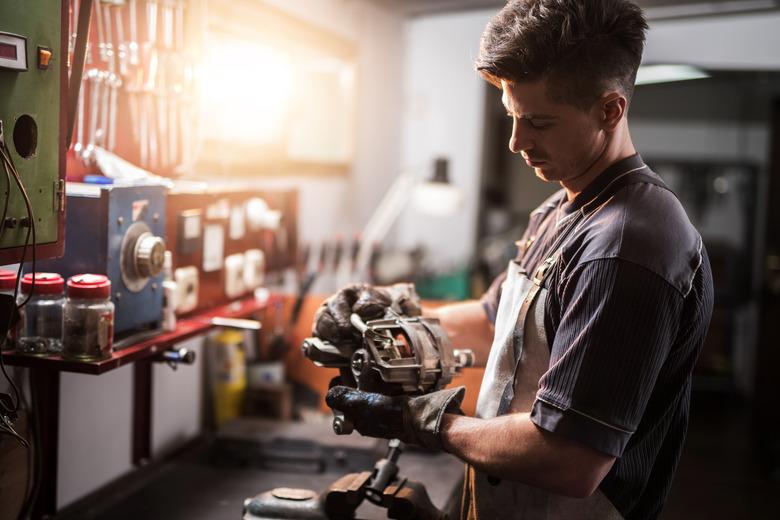 Manual worker repairing electric motor in a workshop.