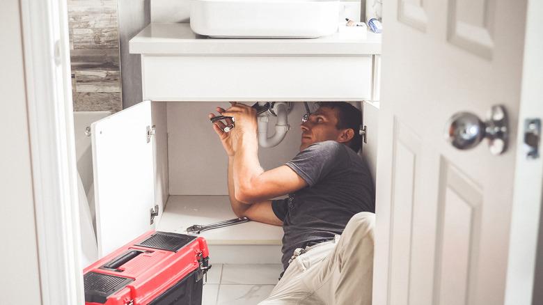 Plumber Man With Tools In the bathroom. Plumbing And Renovation