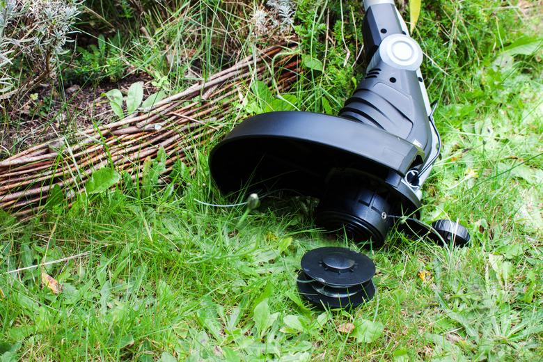 Lawn trimmer against wooden fence close up