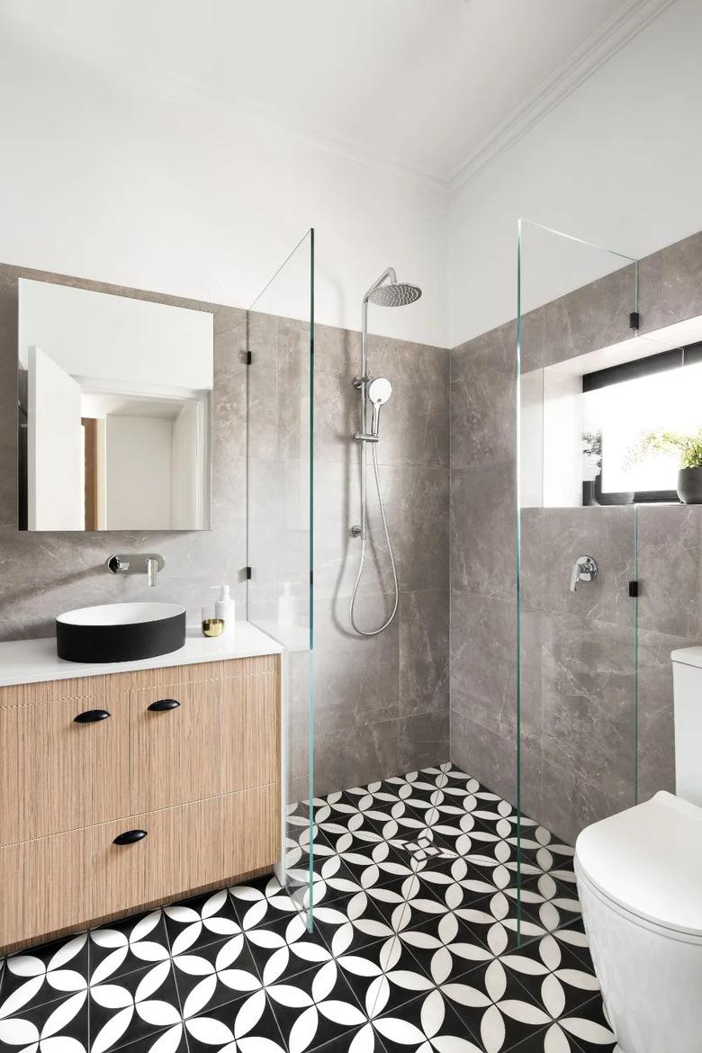 modern shower window idea with black and white patterned floor tile and faux wood vanity