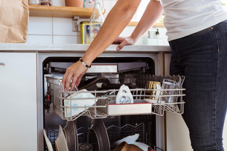 Midsection of woman using dishwasher while standing in kitchen