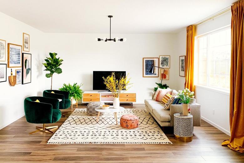 bohemian living room lighting idea with green velvet tub chairs and floor to ceiling drapery