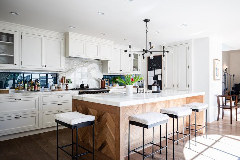 kitchen with white cabinets, decorative wood kitchen island with sink and white stools