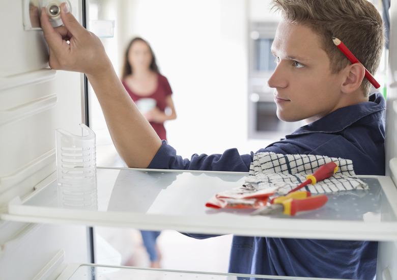 Electrician working on fridge in home