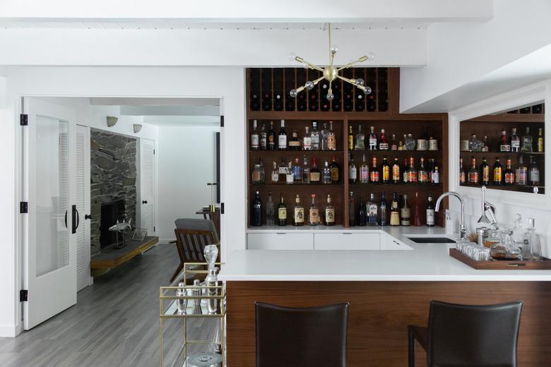 bar with cabinets full of bottles, white stone countertops, bar faucet and sink