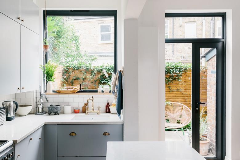 sunny kitchen with L-shaped countertop open to backyard