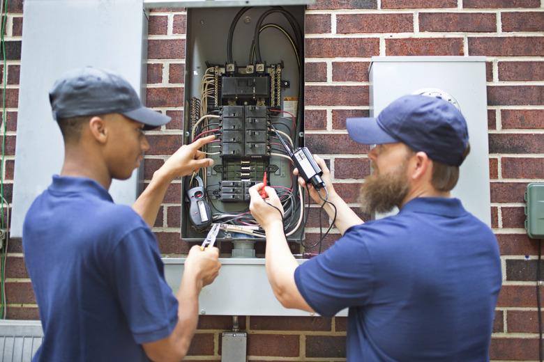 Repairmen, electricians working on home breaker box.