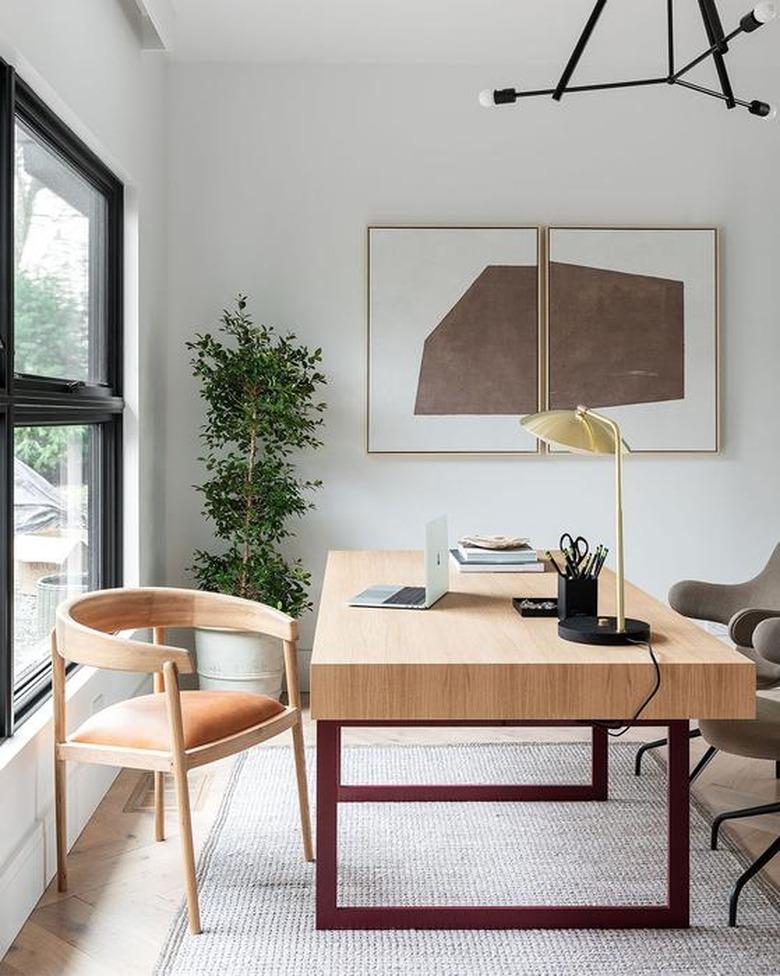 white modern home office with large desk in the center and wall art hanging above