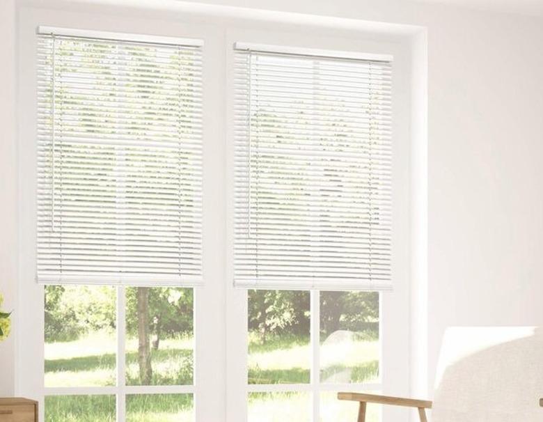 Cordless white blinds in bright, white living room windows.