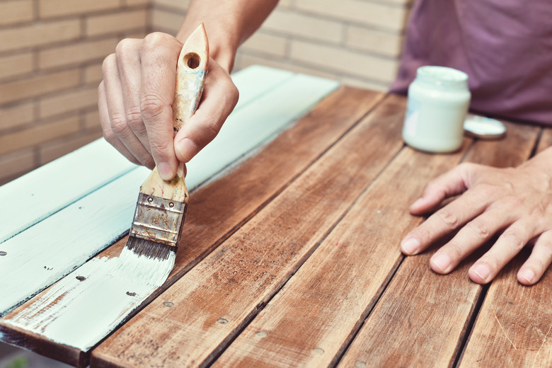 young man painting an old wooden table