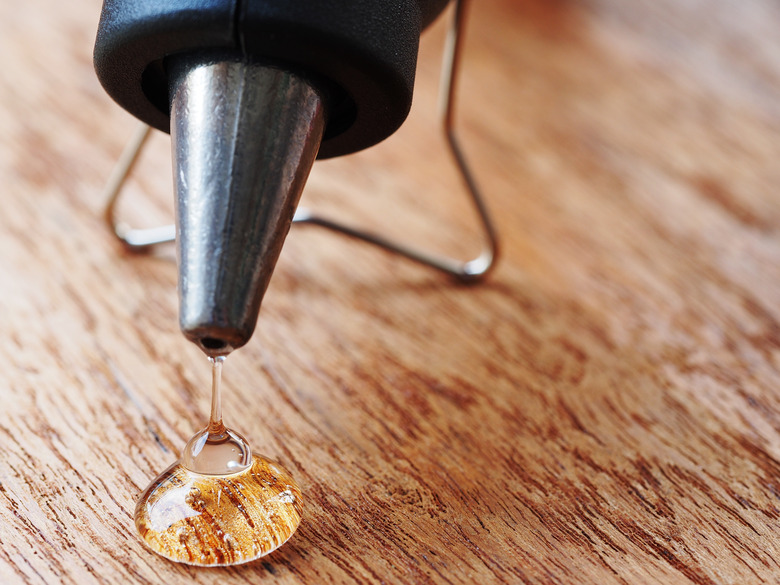 closeup hot glue gun with melted glue dripping out