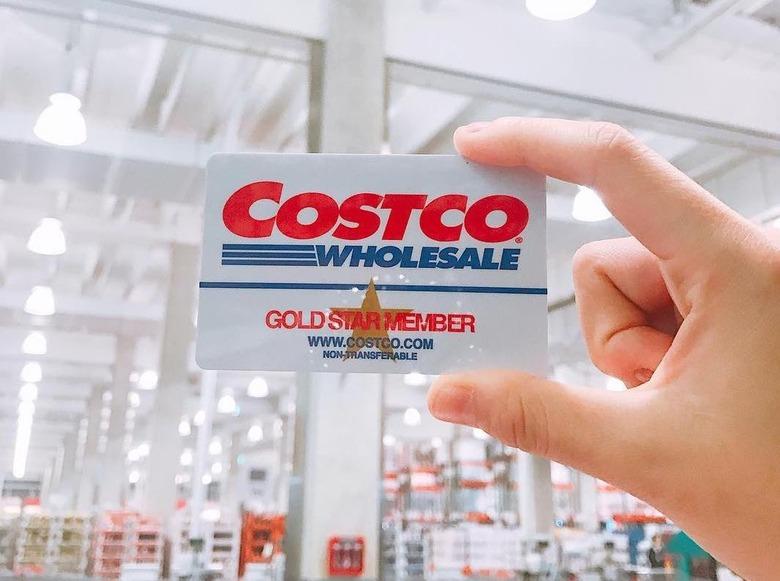 Hand holding up a Costco Gold Star membership card in a Costco store