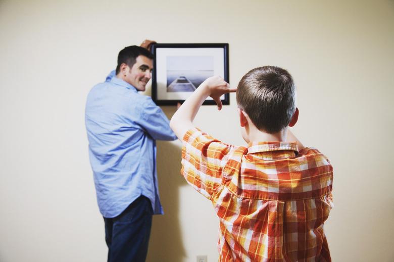 Son helping father straighten picture