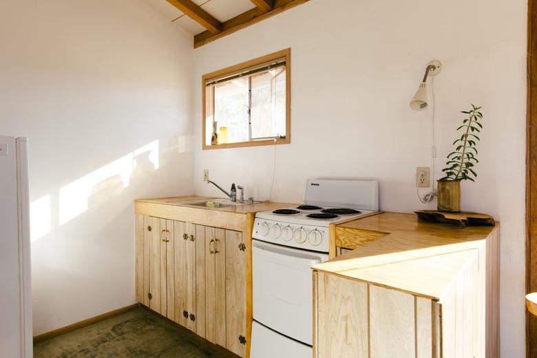 a kitchen with natural wood cabinets and an electric apartment size stove