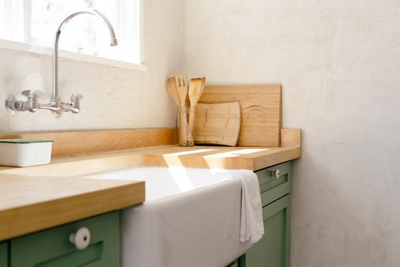 a kitchen with butcher-block counters and cabinetry painted green