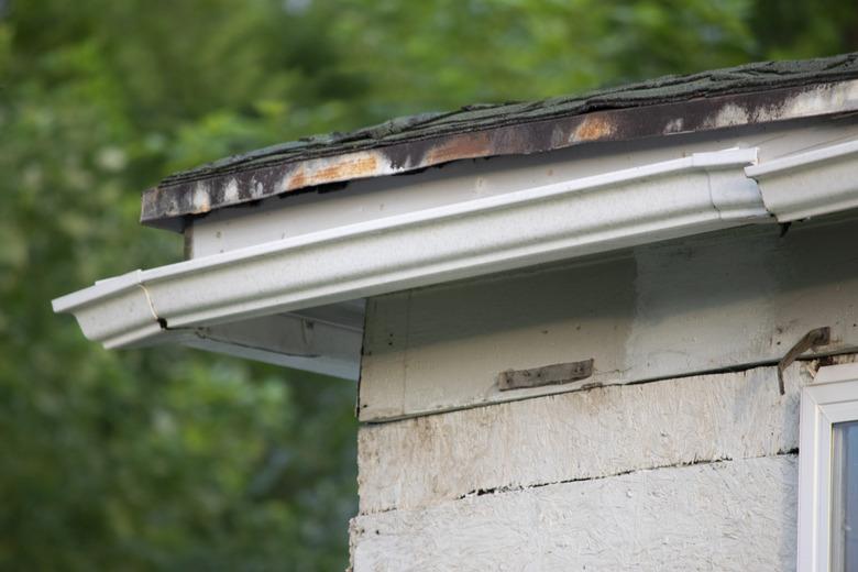 Damaged and old roofing shingles and gutter system on a house