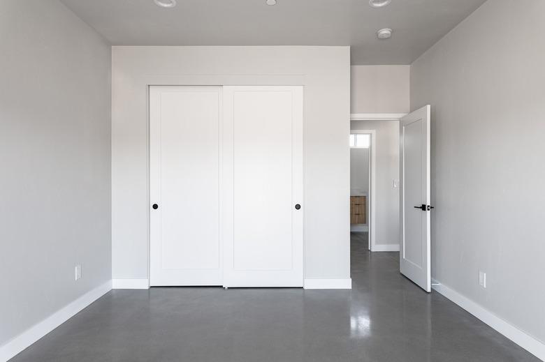 Light gray wall room with white sliding closet doors and dark gray flooring