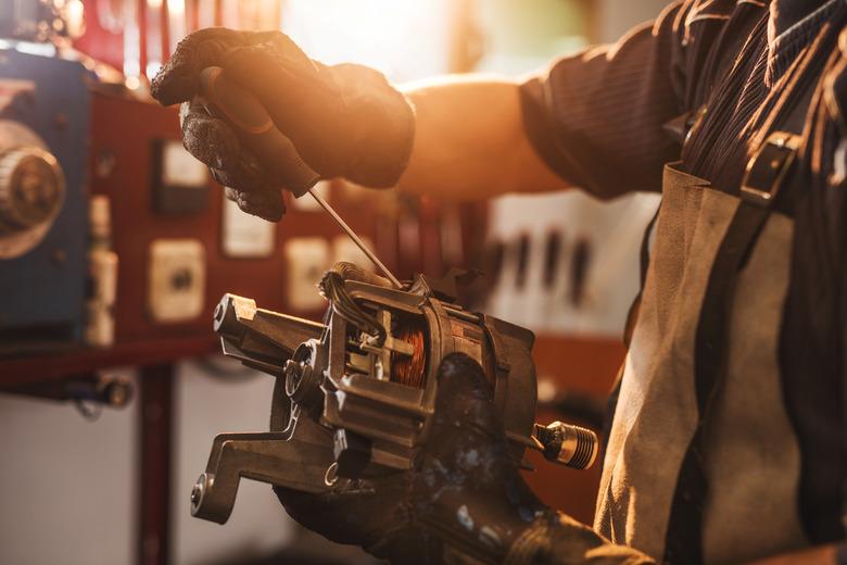 Unrecognizable manual worker working on electric motor.