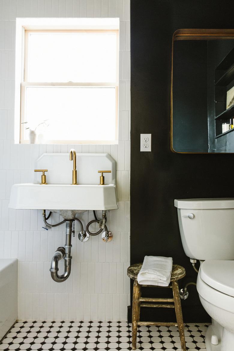 black and white apartment bathroom idea with mirror and stool near toilet