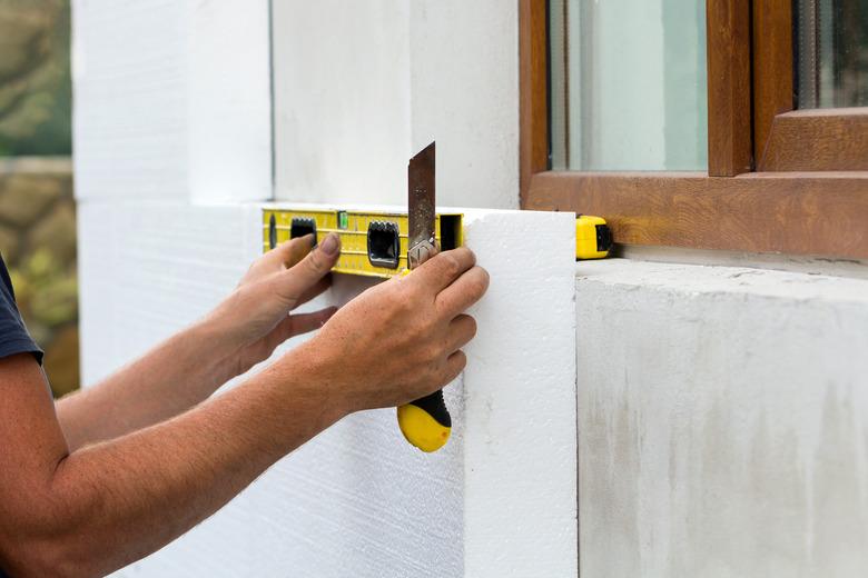 Construction worker insulating house wall with Styrofoam insulation sheets.