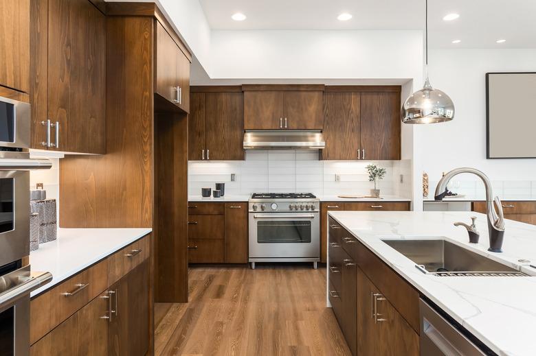 Beautiful kitchen in new luxury home with hardwood floors, waterfall quartz island, and pendant lights.