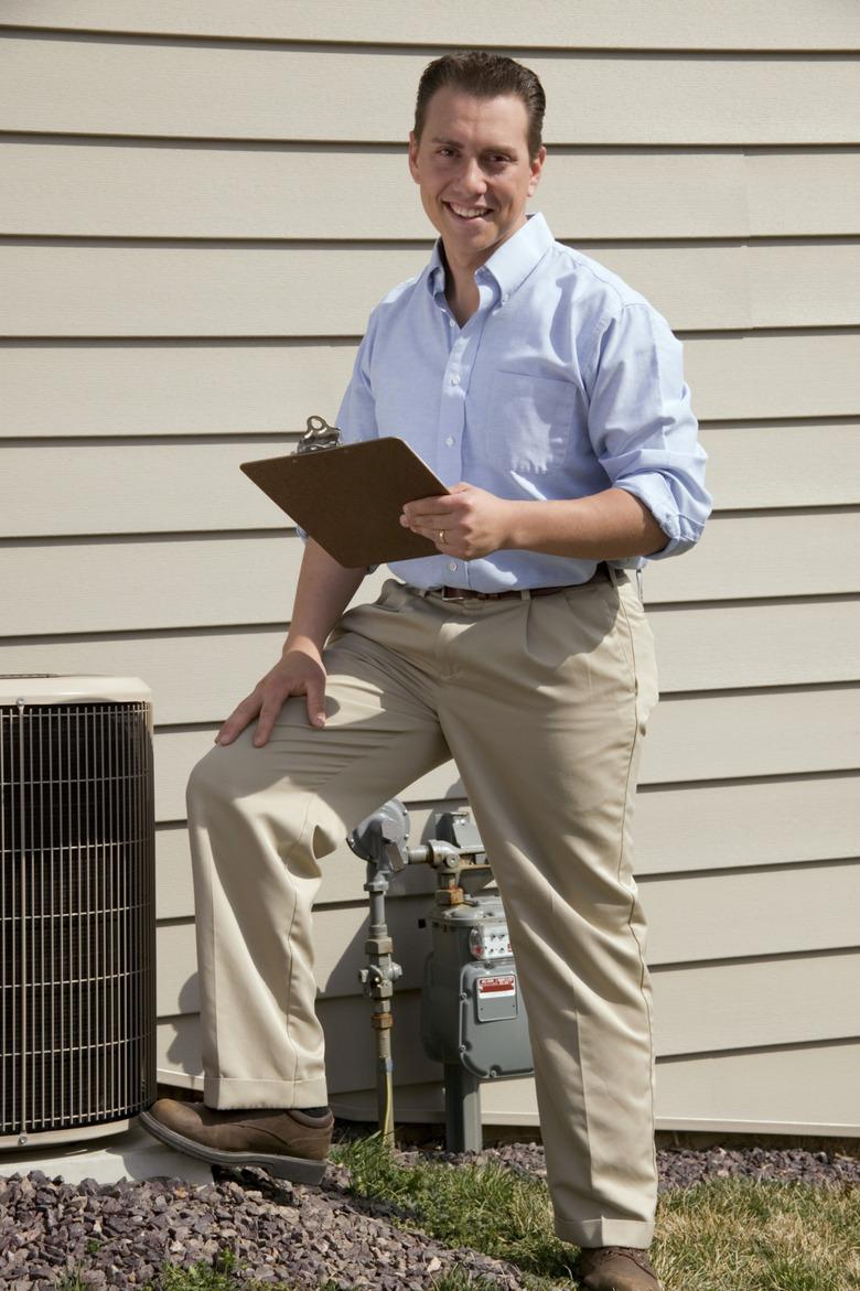 Man with clipboard standing near air conditioning unit