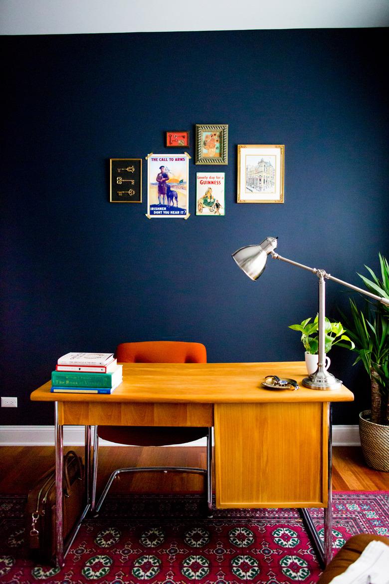 Midcentury modern home office with navy walls and small gallery wall