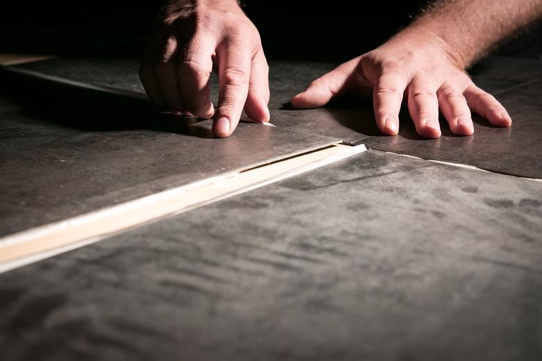 Hand installation of vinyl flooring tiles.