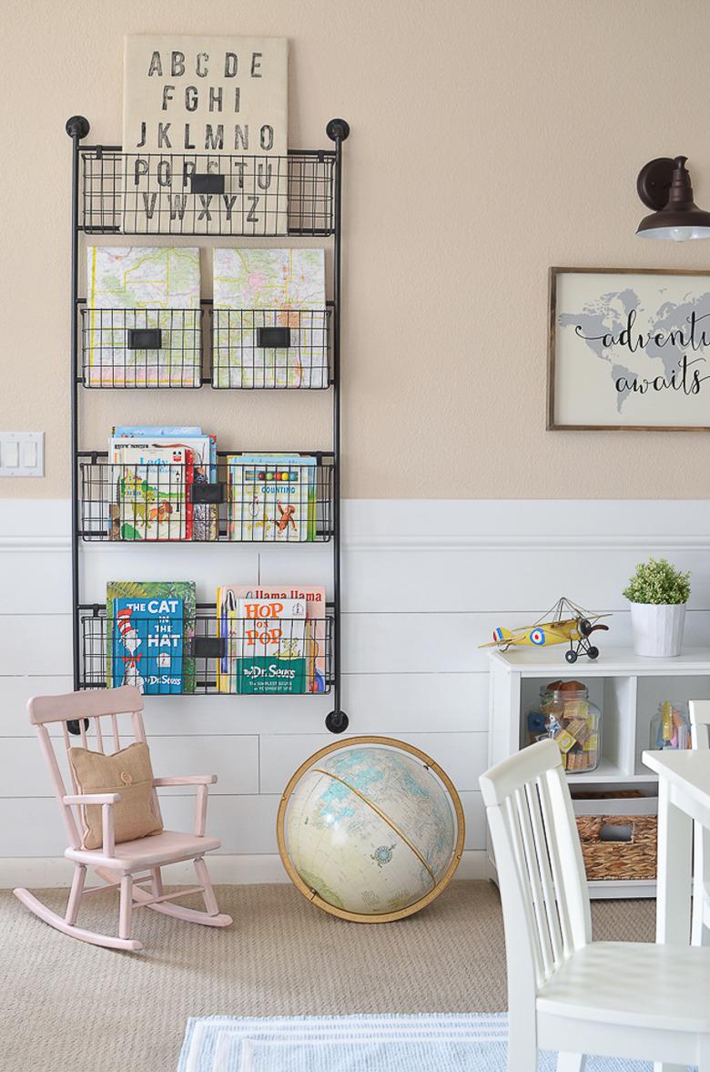 Vertical bookshelf playroom storage idea with blush walls and white furniture