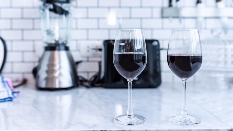 Red wine in the glass In the modern kitchen . Classic white wall background .