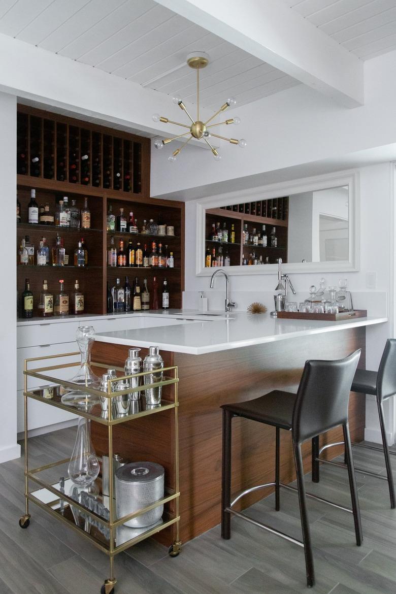 Contemporary Bar with wood, built in wood shelves, modern chandelier, bar cart, black leather bar stools.