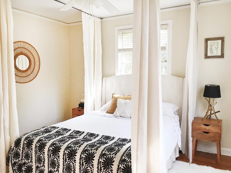 a bed with curtains hanging from the ceiling around it to create a canopy