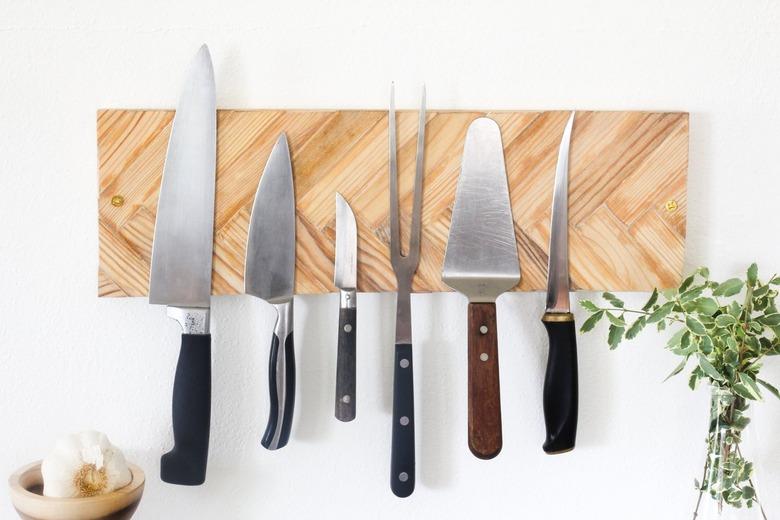 a knife holder made from magnets behind a layer of herringbone paint sticks mounted on a kitchen wall