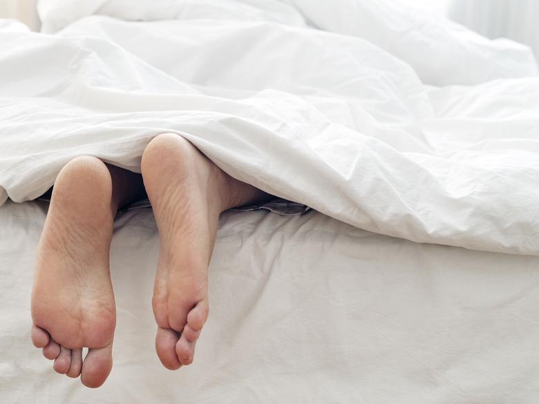 Lazy man and his feet , lying on comfortable bed